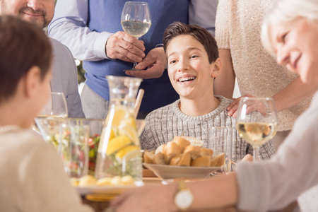 Happy boy celebrating birthday with family, eating festive mealの写真素材