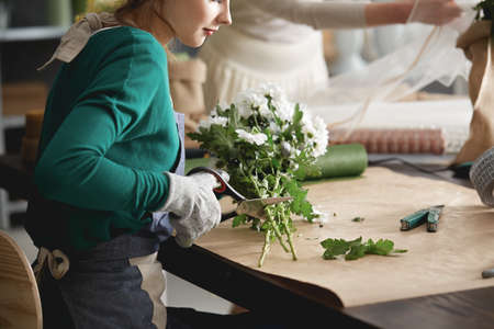 Young florists cutting flowers and making a flower bouquet