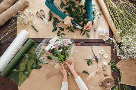 Florists making flower bouquets on a wooden tableの写真素材