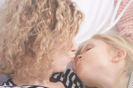 Young mom and her daughter about to kissの写真素材
