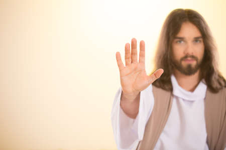Calm Messiah raising palm of hand, isolated on bright background