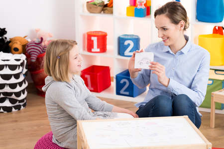 Little blond girl visiting professional speech therapist