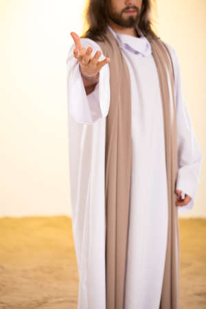 Silhouette of Messiah reaching out hand, standing on sandの写真素材