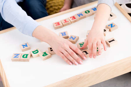 Woman keeping hands on a desk with building blocks with lettersの写真素材