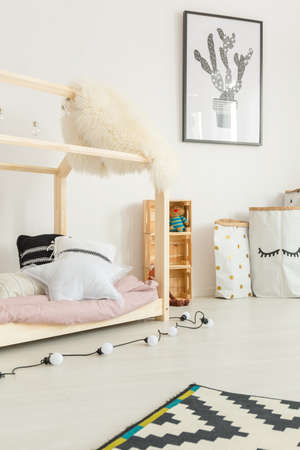 White child room with house bed, carpet, wall poster