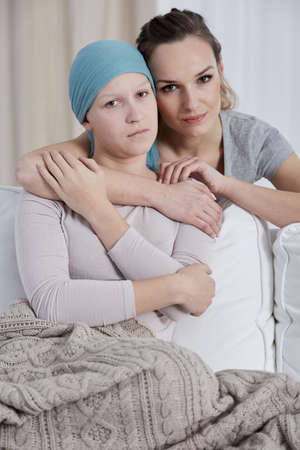 Young serious woman hugging her ill sisterの写真素材