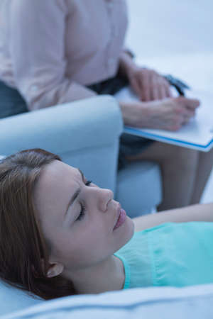 Stressed woman lying on sofa during psychotherapyの写真素材