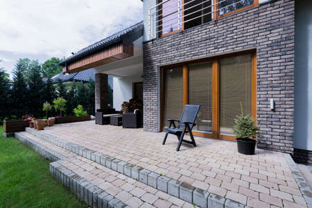 Small concrete terrace with furnitures in modern house with brick elevationの写真素材