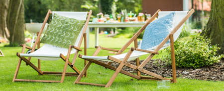 Two deck chairs with pillows in the gardenの写真素材