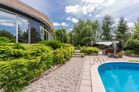 View of a part of a detached modern house and backyard with swimming pool