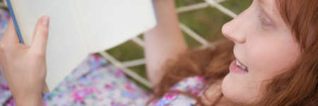 Woman lying on a hammock and lost in a bookの写真素材