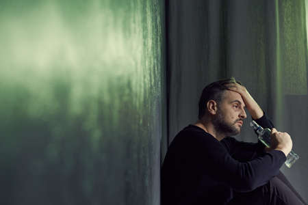 Depressed tired alcoholic drinking vodka from a bottleの写真素材