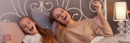 Happy mother and daughter watching movie in the evening togetherの写真素材