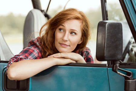 Beautiful ginger woman sitting in blue carの写真素材