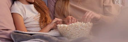 Close-up of mother and daughter eating popcorn from bowlの写真素材