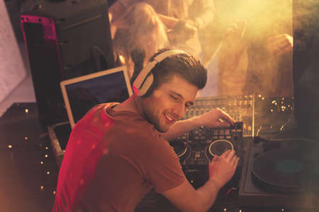 Happy dj playing music on mixer with vinyl record