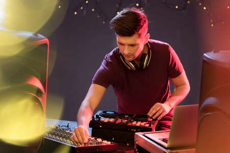 Passionate dj at turntable, playing music at disco club