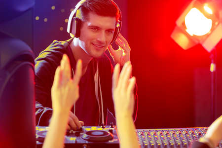 Young disc jockey giving concert at nightclub