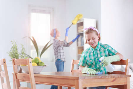 Smiling girl wiping the table in a dining room