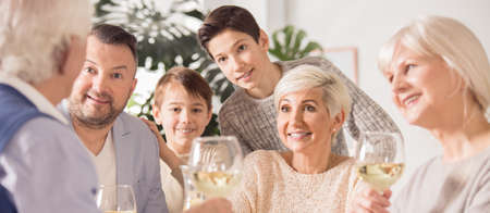 Family with kids and grandparents enjoying meal in summer house