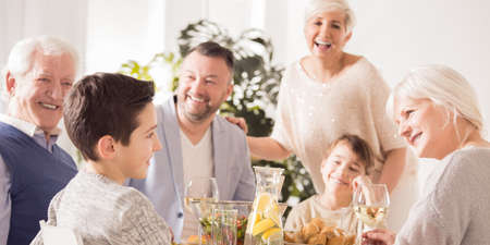 Happy smiling family talking and eating meal together during holidays