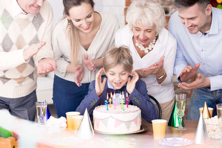 Happy parents, grandparents and birthday boy blowing out candlesの写真素材