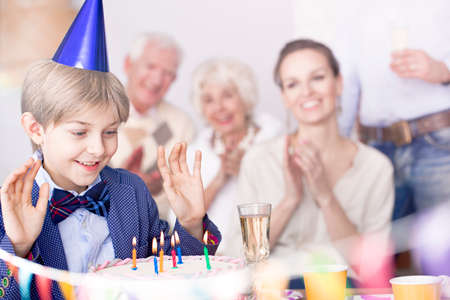 Happy family and boy making birthday wishの写真素材
