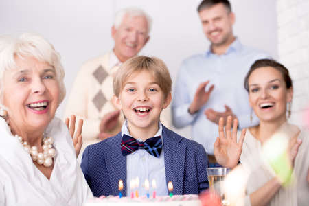 Loving family having birthday party, standing above cake with candlesの写真素材