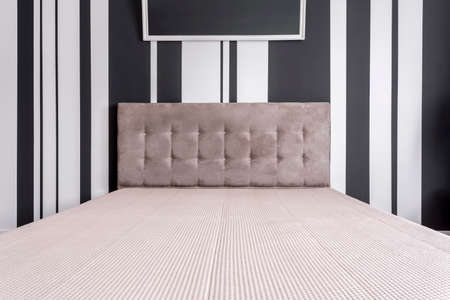 White and grey bed by the black and white wall with stripes