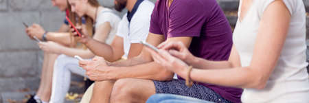 Group of people sitting outdoors and textingの写真素材