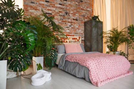 Plants in modern bedroom with brick wall and bedの写真素材