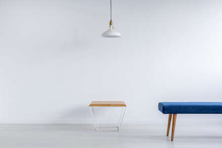 Blue bench and wooden coffee table in empty white roomの写真素材