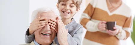 Little smiling boy playing and having fun with grandpa
