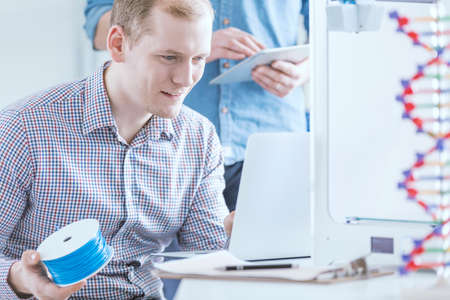 Man holding filament roll preoccupied with 3D printing