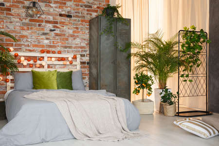 King-size bed in modern bedroom decorated with plants and cotton ballsの写真素材