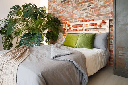 Modern bedroom with brick wall, king-size bed and monsteraの写真素材
