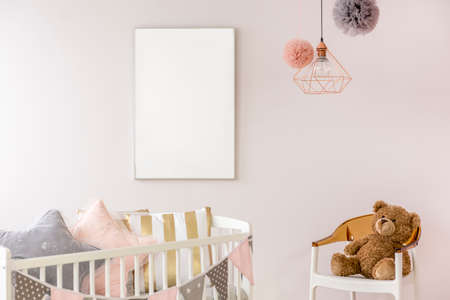 Newborn bedroom with white crib, chair, copper lamp, teddy bearの写真素材