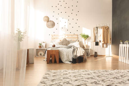 Trendy spacious bedroom interior with dots on the wall and bedsheets