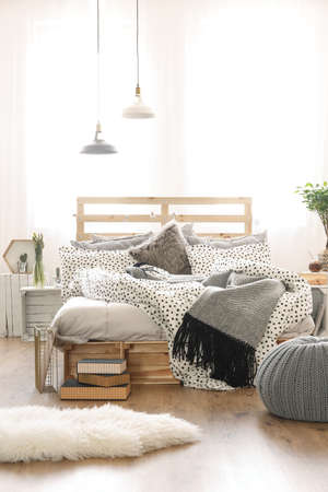 Wooden bed in stylish bedroom with grey accessories