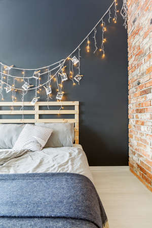 Cozy bedroom with black and red brick wall and wooden bedの写真素材