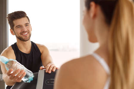 Handsome, personal trainer holding bottle of waterの写真素材
