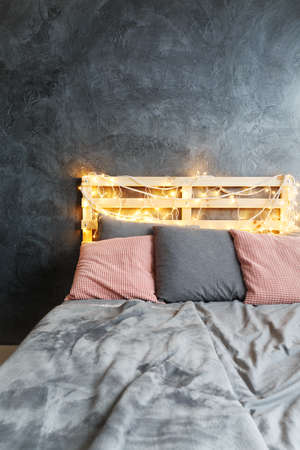 Cozy comfortable bed with light chain in grey bedroomの写真素材