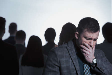 Young businessman rejected from a crowd and standing back to back with dark silhouettes