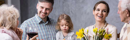 Smiling young marriage with a little boy sitting at a family table with their elderly parentsの写真素材
