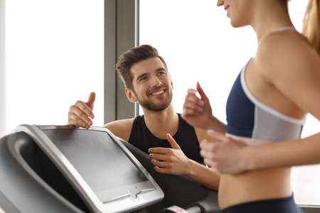 Personal trainer and woman running on electric treadmillの写真素材