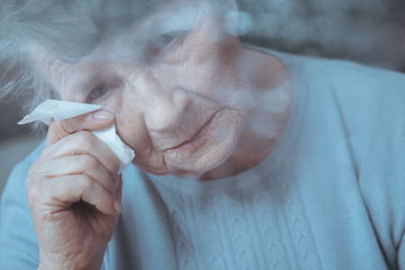 Portrait of sad, lonely senior woman crying, holding tissueの写真素材