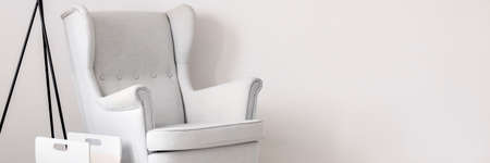 Panoramic picture of a white armchair against a white wall