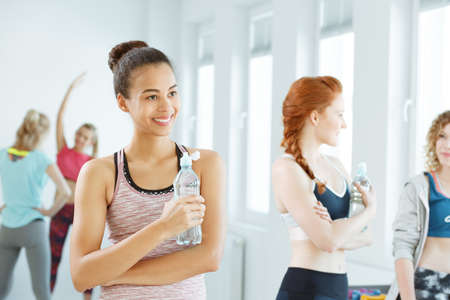Active young women drinking water after fitness classes