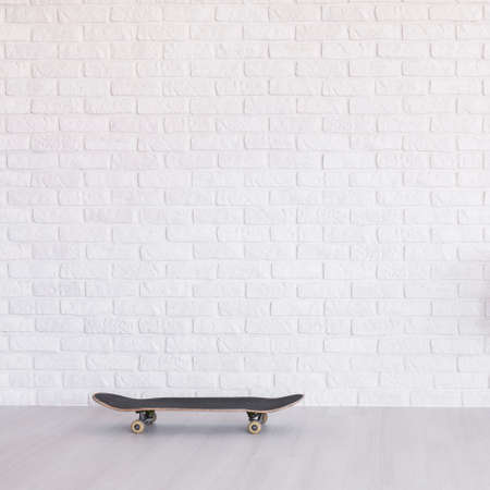 Skateboard in empty light interior with flooring and white brick wallの写真素材