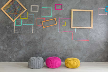 Room with decorative grey wall plaster, colorful poufs and framesの写真素材